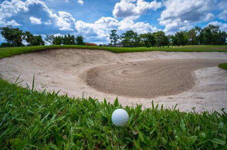 Golf ball in green golf course with white cloud and blue skyの写真素材