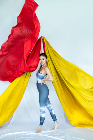 acrobat athletic, Beautiful young asian woman gymnast training exercise with red fabrics isolated on studio backgroundの写真素材