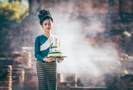 Beautiful woman dressed in Thai national costumes and put the krathong on the hand, Loy krathong tradition that paid respects to the water spirits. The word krathong refers to basket and loy means to floatの写真素材