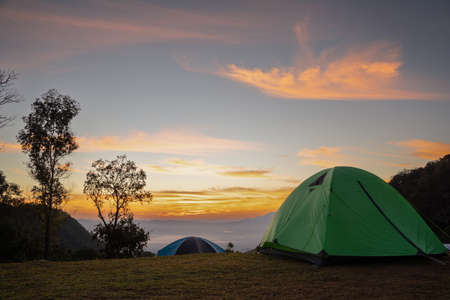 Vivid tents with awesome view to high mountain range under first light of sun in sunrise sky. Scenic...