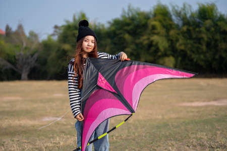 Young woman playing kite at the grass field. asian girl flying a kite in summerの写真素材