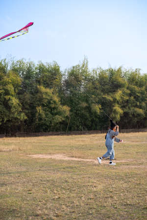 Young woman playing kite at the grass field. asian girl flying a kite in summerの写真素材