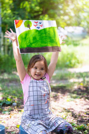 Proud little girl showing her painting, Cute little girl in art school shows her watercolor paintingの写真素材