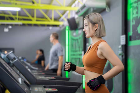 Young woman doing indoor running in a fitness club. Asian woman workout in gym. Concept of sports,...