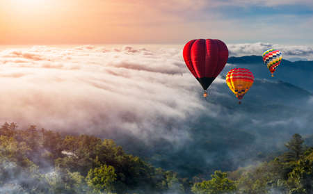 Hot air balloons above high mountain at sunrise, sunset. Colorful hot-air balloons flying over the mountainの写真素材