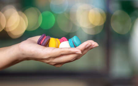 Hand holding Sweet and colourful french macaroons or macaron. Mini macaroons in female hand.の写真素材