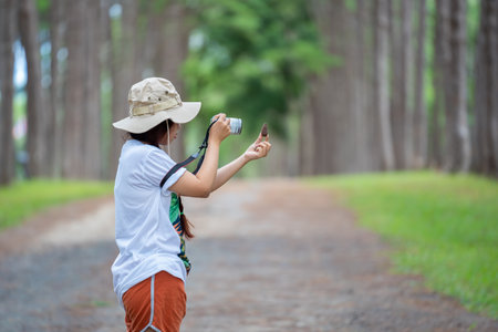 Woman's hand holding a pine cone with a natural blurred background. Outdoor winter lifestyle portrait of young woman holds a pine cone in her hand in forest with camera travel photo of photographer.の写真素材
