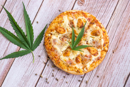 Homemade pizza with marijuana or cannabis leaves on wooden background. Fresh medical marijuana, cannabis decorate on pizza.の写真素材