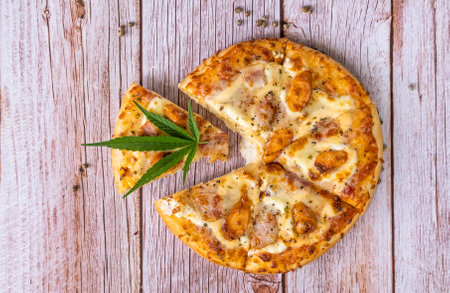 Homemade pizza with marijuana or cannabis leaves on wooden background. Fresh medical marijuana, cannabis decorate on pizza.の写真素材