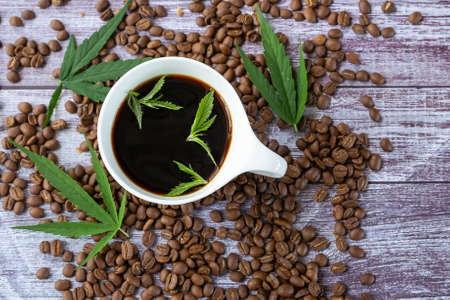 Top view of Cannabis coffee - marijuana leaf on coffee cup and coffee beans. Coffee with herbal ingredients, cannabis drink concept.の写真素材