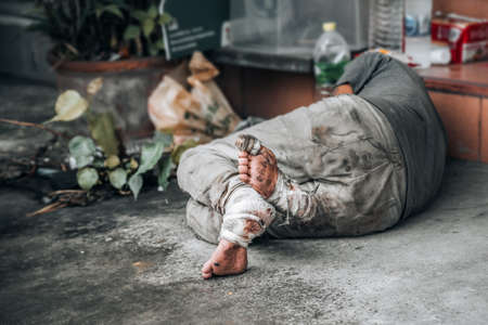 Homeless man sleeps on the street in front of the shop and begging for help and money. Problems of big modern citiesの写真素材
