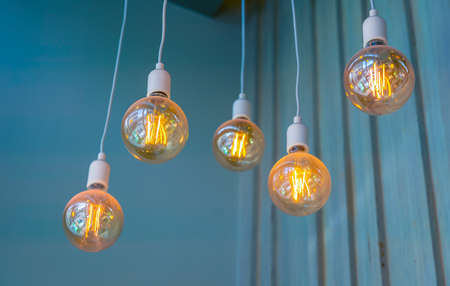 Vintage tungsten filament multiple lamps hanging from the ceiling on a white wires as an interior design concept. Energy and design conceptの写真素材