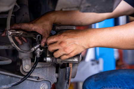 Male car mechanic examining brake disc.Car brake repairing in garage.Selective focus disc brake on...