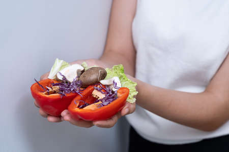 Woman hands holding bell pepper, mushroom, purple cabbage and lettuce in the kitchen.