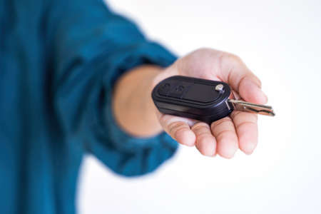 Car Keys. Seller hand giving keys. A business woman holding a car key isolated on white backgroundの写真素材