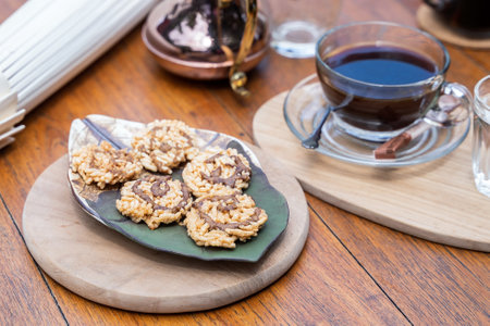 Sweet crispy rice cakes topping with cane sugar on plate and hot coffee in park. Thai snack.の写真素材