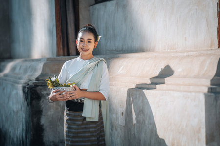 Chiangmai Province, Thailand, 13 October 2022 : Beautiful women in Thai northern style costume holding a silver bowl with flowers at old temples ,women at northern Thai templeのeditorial素材