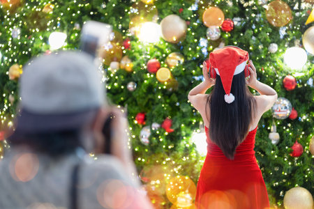 Young woman in Santa Claus clothes with headphone being photographed by photograhperの写真素材