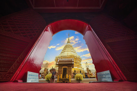 Image of Chedi Phra That Doi Suthep was photographed through the red church gate with sunset sky. contrasting between the golden pagoda of Phra That Doi Suthep in Chiang Mai, Thailand.の写真素材