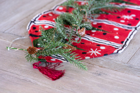 Pine branch and pine cone on red Christmas cloth on wooden tableの写真素材
