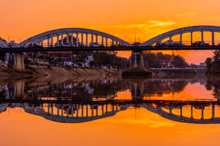 Lampang white bridge across Wang river called "Ratsadaphisek Bridge" in sunset, sunrise and reflection, It is regarded as one of the landmarks of Lampang Province, Thailand.の写真素材