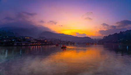 Tourists take a boat with mist fog over lake in morning at Ban Rak Thai village in Mae Hong  Son province, Thailand.の写真素材