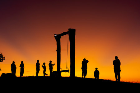 Group of people on top of a mountain in sunset. Silhouette of friends on hill and swing with golden sunset background. hikers celebrating success on top of a hill in the sunsetの写真素材