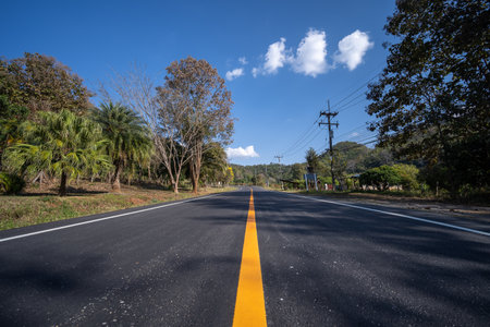 Asphalt road and green tree under blue sky. Road and mountain background. empty asphalt road , Country Road, Transportationの写真素材