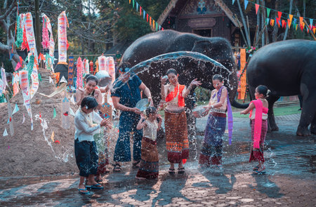 Asian people wearing Thai dress traditional playing splash water with pile of sand pagodas, kite paper and Thai elephant at temple during Songkran festival is funny festival traditional holidayの写真素材