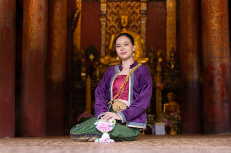 Asian beautiful lady wearing in Thai dress costume traditional according Thai culture and tradition holding Thai Jasmine garland at the ancient wooden temple Chiang Mai, Thailand. Portrait Thai womanの写真素材
