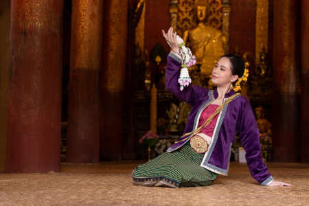 Asian beautiful lady wearing in Thai dress costume traditional according Thai culture and tradition holding Thai Jasmine garland at the ancient wooden temple Chiang Mai, Thailand. Portrait Thai womanの写真素材