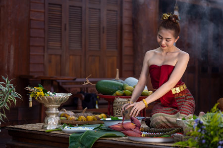 Asian women wearing Thai traditional Lanna style dresses cooking Thai traditional food in the Thai ancient house Chiang Mai, Thailand. Thai women is providing ingredients for cooking. Thai culturalの写真素材