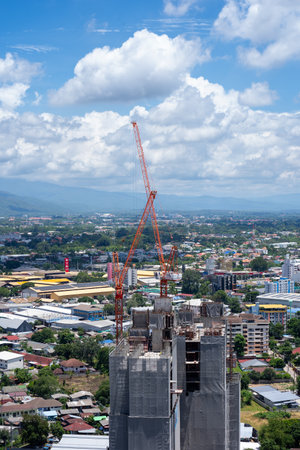 11 July 2023, Chiang Mai, Thailand : Construction cranes at building site in Chiang Mai downtown. Two of tower Construction site with cranes and building with blue sky background, City developmentのeditorial素材