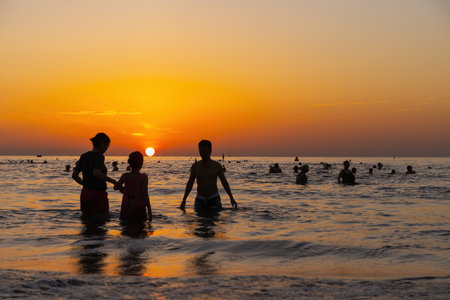 Danang, Vietnam - August 15, 2023 - Sunrise at My Khe beach, Danang, Vietnam. Da Nang locals and tourists exercise along Da Nang beach, silhouette people walking seaside, relaxing, jogging on beachのeditorial素材
