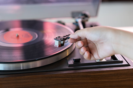Close up woman hand put the needle on a record, playing vinyl disc at the party. Female dropping the needle on a long playing vinyl record. Music on vinyl discs.の写真素材