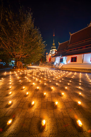 candles ligt around it in a temple. Candles burning around in area of front of chapel or church. Light of Lanna Candle Trays in loy krathong night. Yi peng festival Chiang Mai Thailand.の写真素材