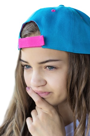 teen girl with a wistful face in a multi-colored baseball cap on a white background. Isolatedの写真素材