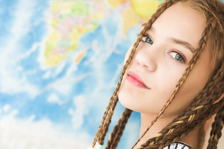 Portrait of a beautiful girl face close-up on a world map background. Soft natural light. The concept of serenity with copy spaceの写真素材