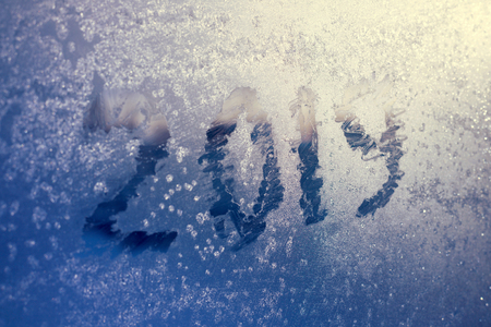 inscription  2019 on a frozen window in hoarfrost. Scratched numbers on blue cold winter backgroundの写真素材