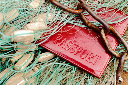 Passport lies on a fishing net and tangled with a rusty chain. The concept of punishment for illegal...