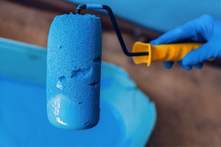 Gloved hand holding the roller above the paint tray. Services painter. Repair and decoration of apartments.の写真素材