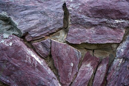 Decorative laying from a natural stone of claret color and cement close up. Abstract background. Textured and rough surface.の写真素材