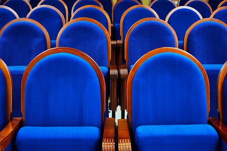 A row of velvet blue armchairs with wooden armrests in the meeting room.