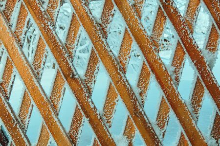 A wooden grate or fence is covered with frost.