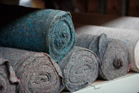 Covering non-woven material in rolls on the shelves of the warehouse. Stocks of cloth and rags. Copy space.の写真素材