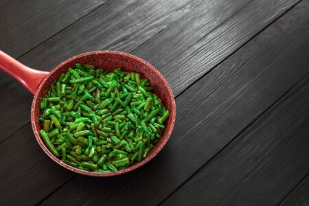 Cooked green beans in a frying pan on a black wooden background. Space to copy. Top view .の写真素材
