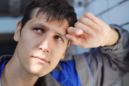 Young man sad in thought at the workplace. Concept of downsizing and job loss