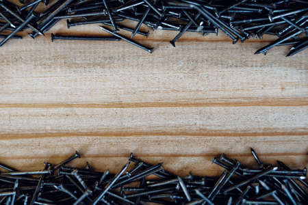 Small nails are scattered on the wooden Board. Background with space to copy. Advertising nails on...