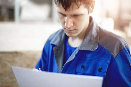 A warehouse employee takes inventory of the product. A young man of Caucasian appearance checks...