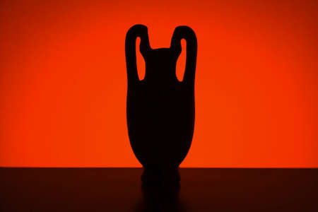 Antique vessel. Silhouette of a vase or amphora against the setting sun. Studio shotの写真素材